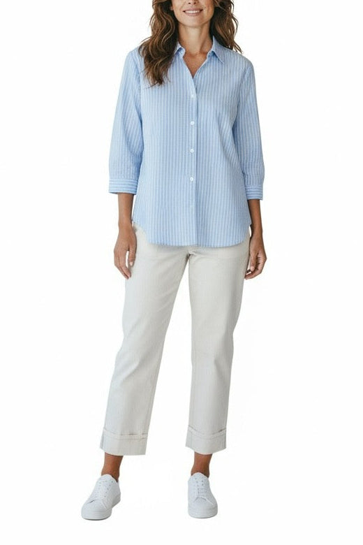 Woman wearing a light blue checkered shirt and white pants on a white background