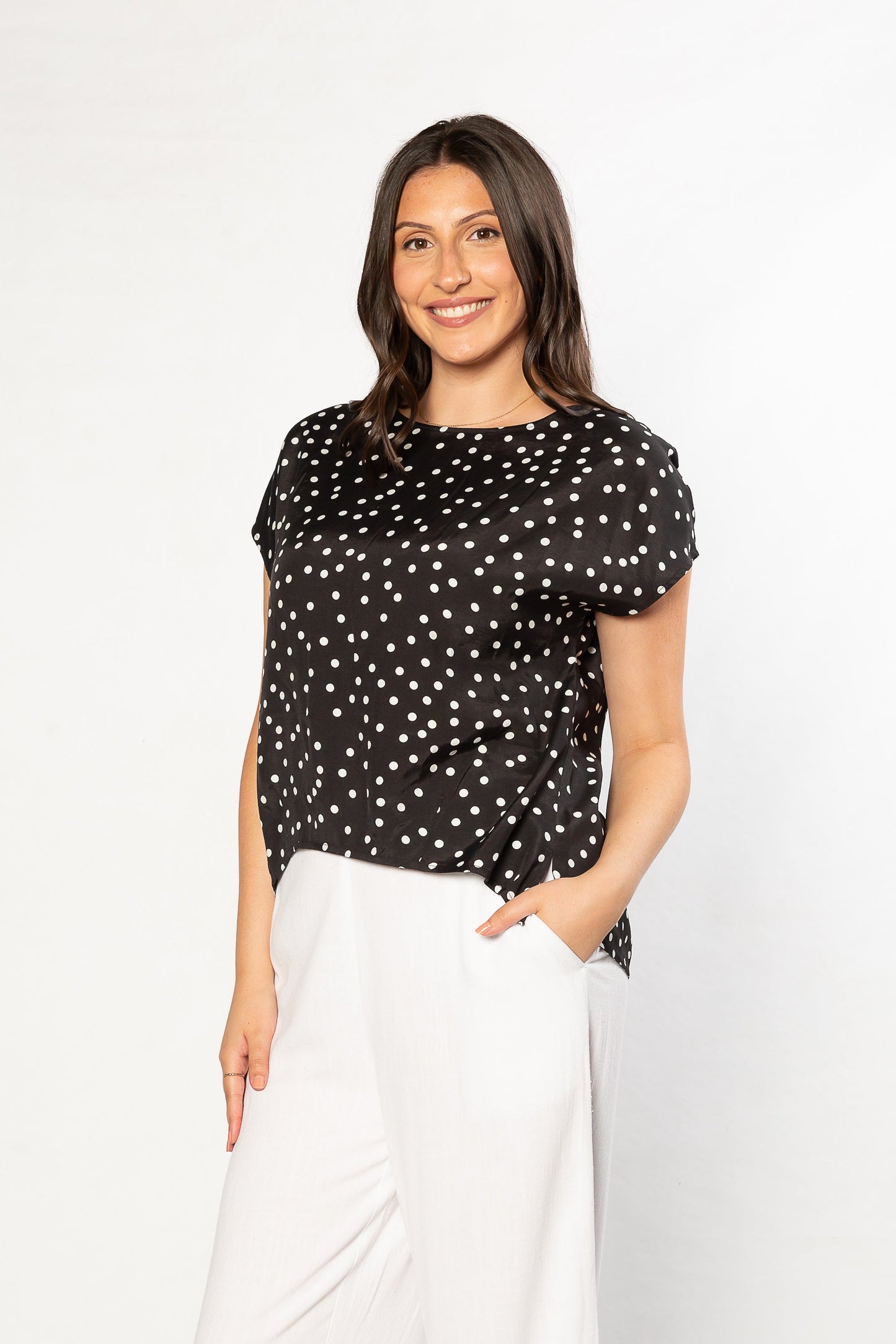 Woman wearing a black polka dot top and white pants, Equinox clothing chic outfit for women over 50