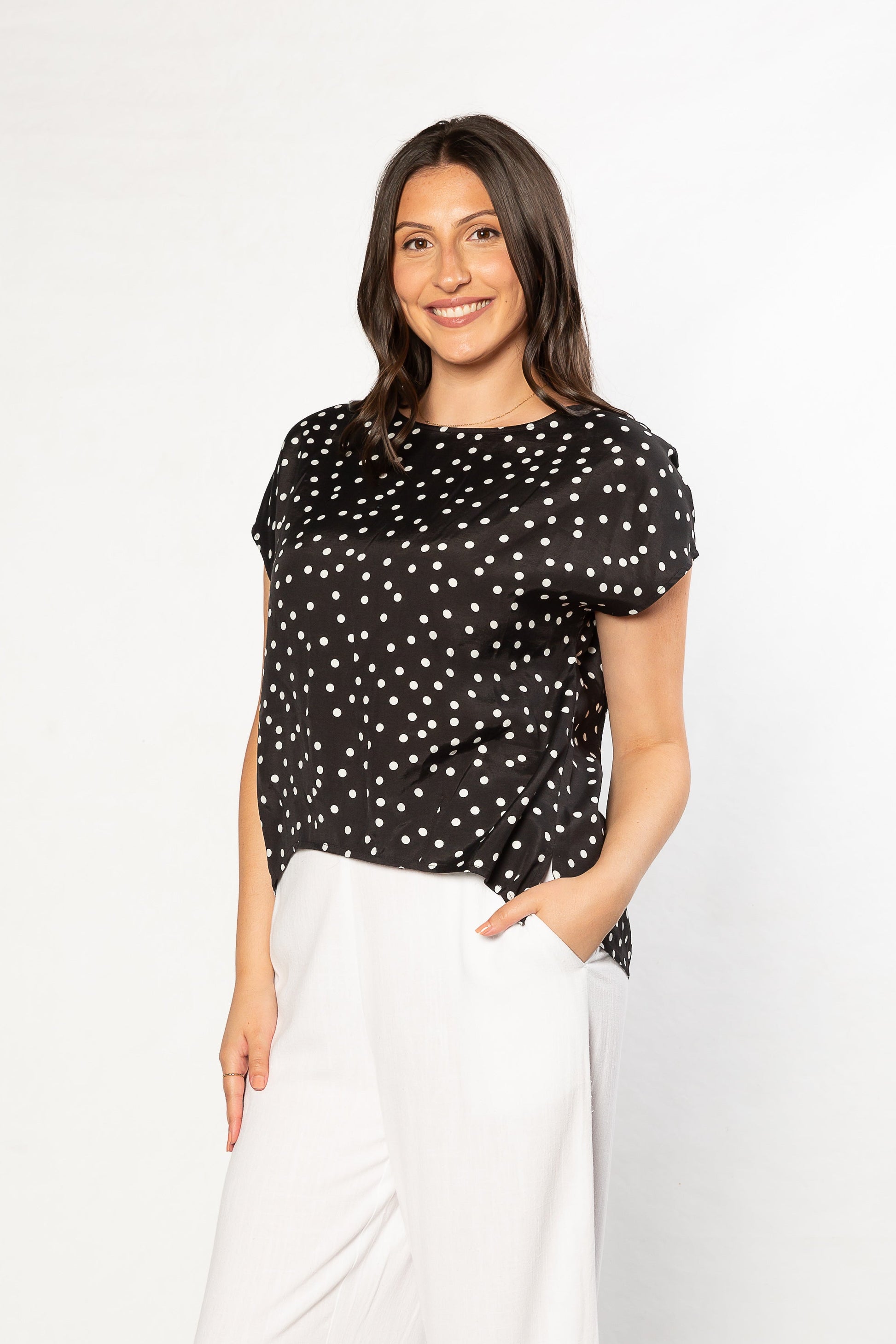 Woman wearing a black polka dot top and white pants, Equinox clothing chic outfit for women over 50