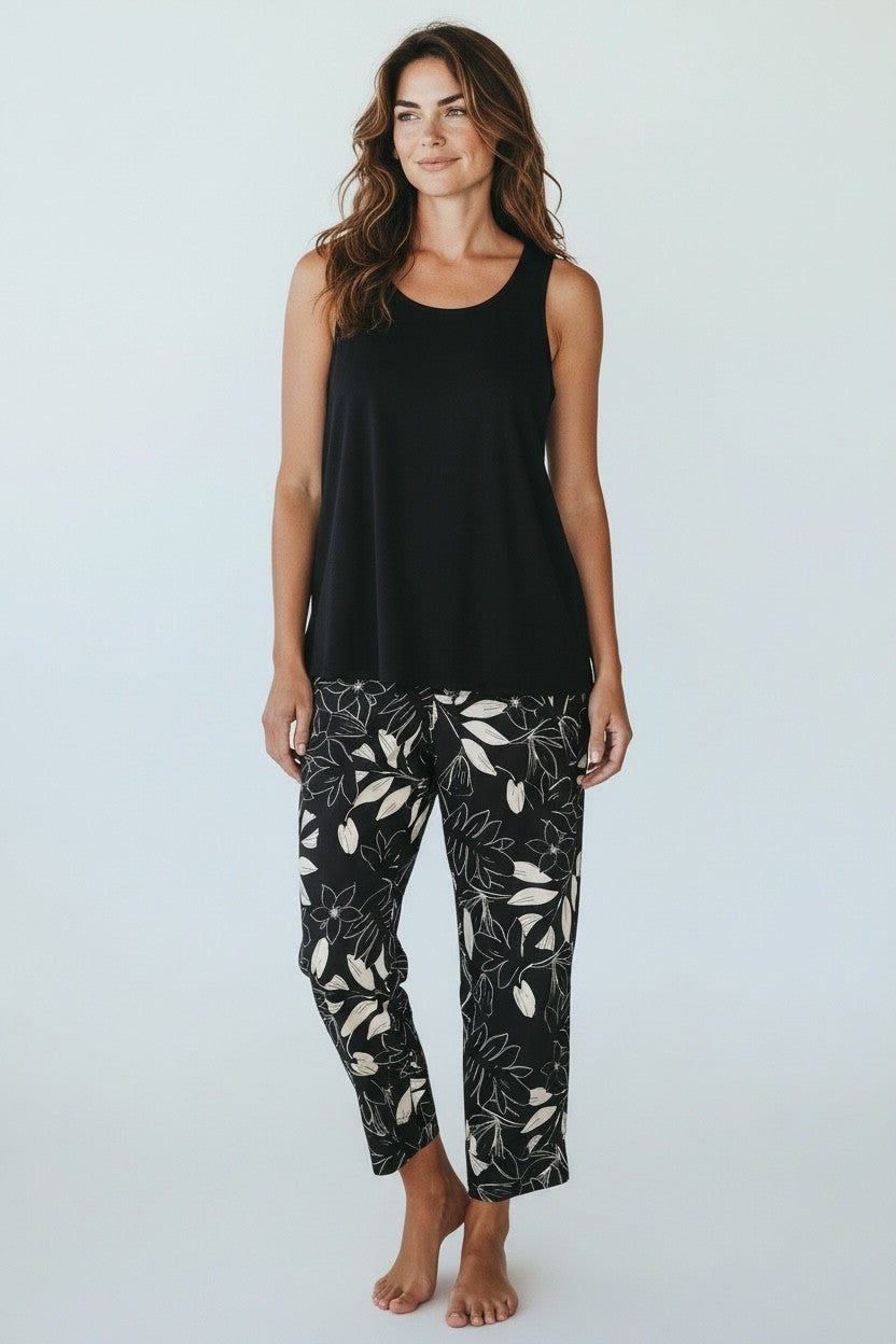 Model wearing Equinox Clothing #6715 Black/White leaf print cropped bengaline pants with a loose black top, in a studio.
