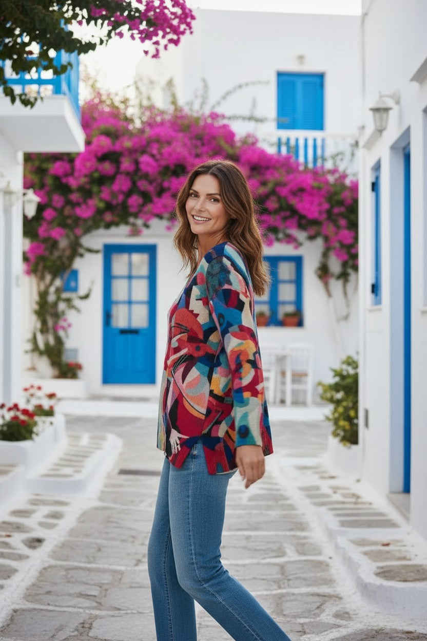 Equinox Clothing printed V-neck knit sweater in Musica pattern worn by a woman with blue jeans in a Greek village