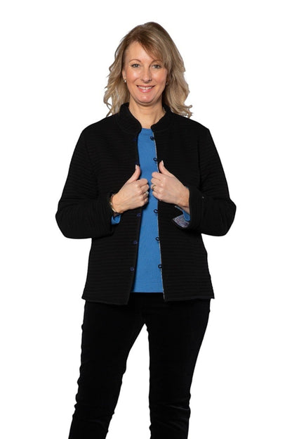 Model wearing Equinox Clothing reversible oriental jacket in black with blue lining, featuring a textured finish.