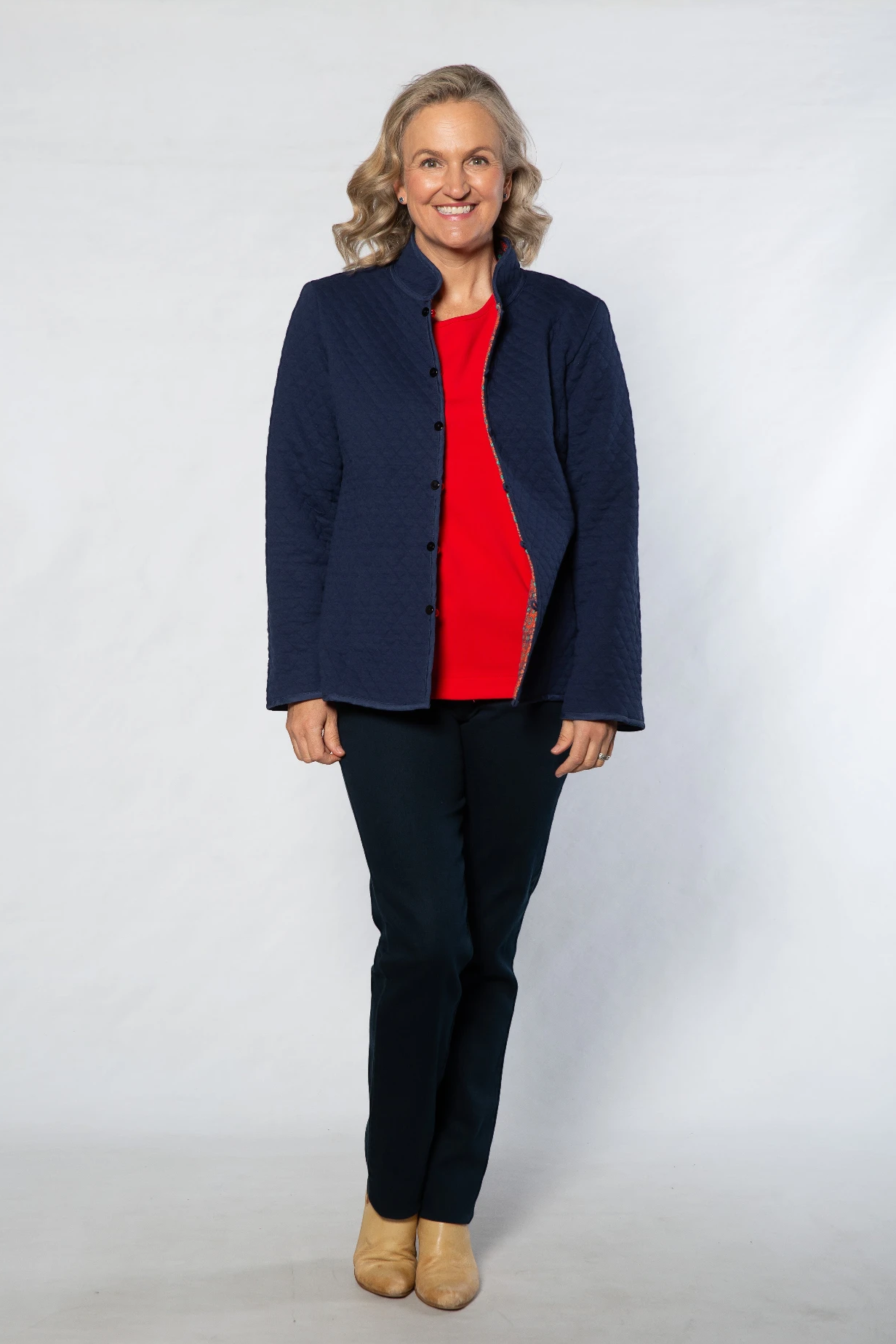 Model wearing Equinox Clothing reversible oriental quilted jacket in navy, showing a red interior and button front.