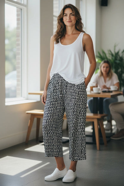 Equinox Clothing white sleeveless stretch cotton tank top worn by a model with patterned wide-leg trousers