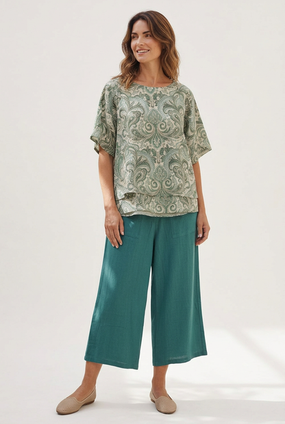 Full-length angled view of a model wearing Equinox Clothing teal linen-blend wide leg culottes #6678 with a paisley top and beige flats.