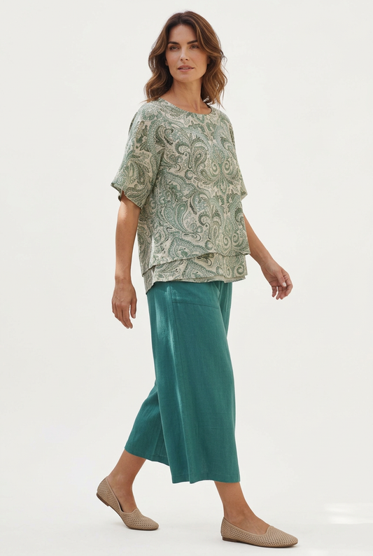 Full-length walking view of a model wearing Equinox Clothing teal linen-blend wide leg culottes #6678 with a paisley top and beige flats.