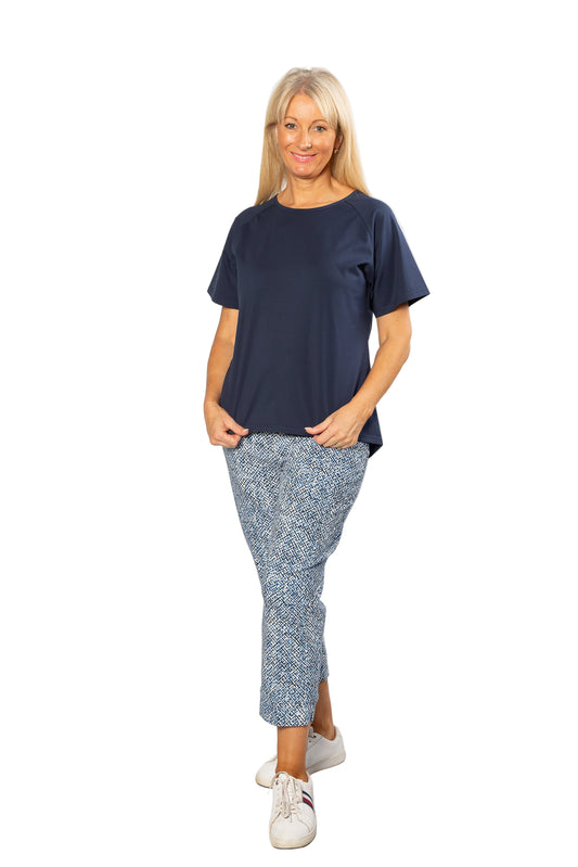 Woman wearing a navy blue top and patterned pants on a white background